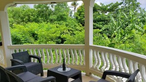 An outdoor patio with wicker furniture and a white balustrade.