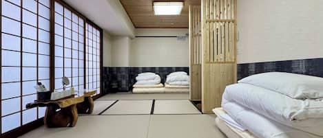 A traditional Japanese room with tatami flooring, a futon bed, a wooden sliding door, and a shoji screen.