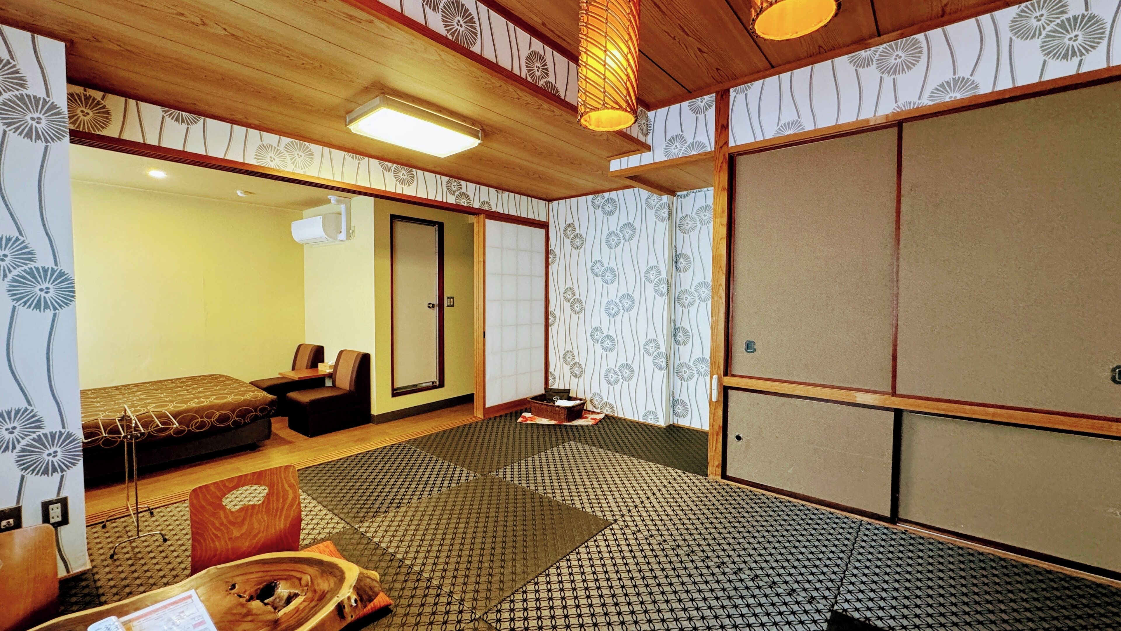 A traditional Japanese-style room with tatami flooring, a low wooden ceiling, and sliding shoji doors.