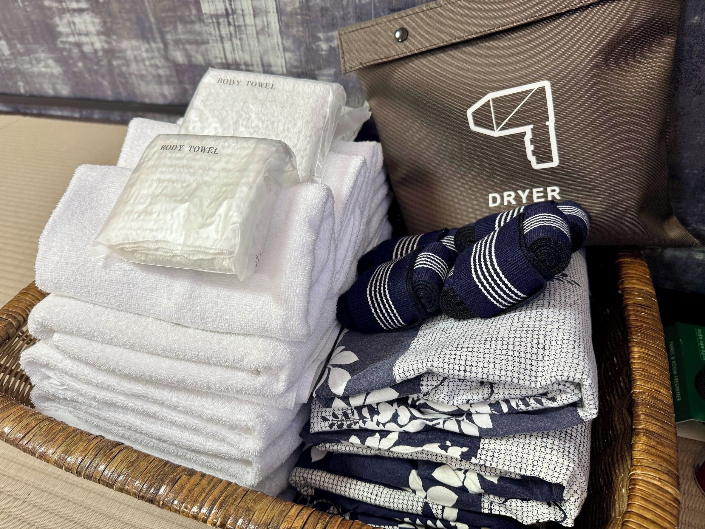 A basket with neatly folded white towels, a pair of striped socks, and a brown bag labeled "DRYER".