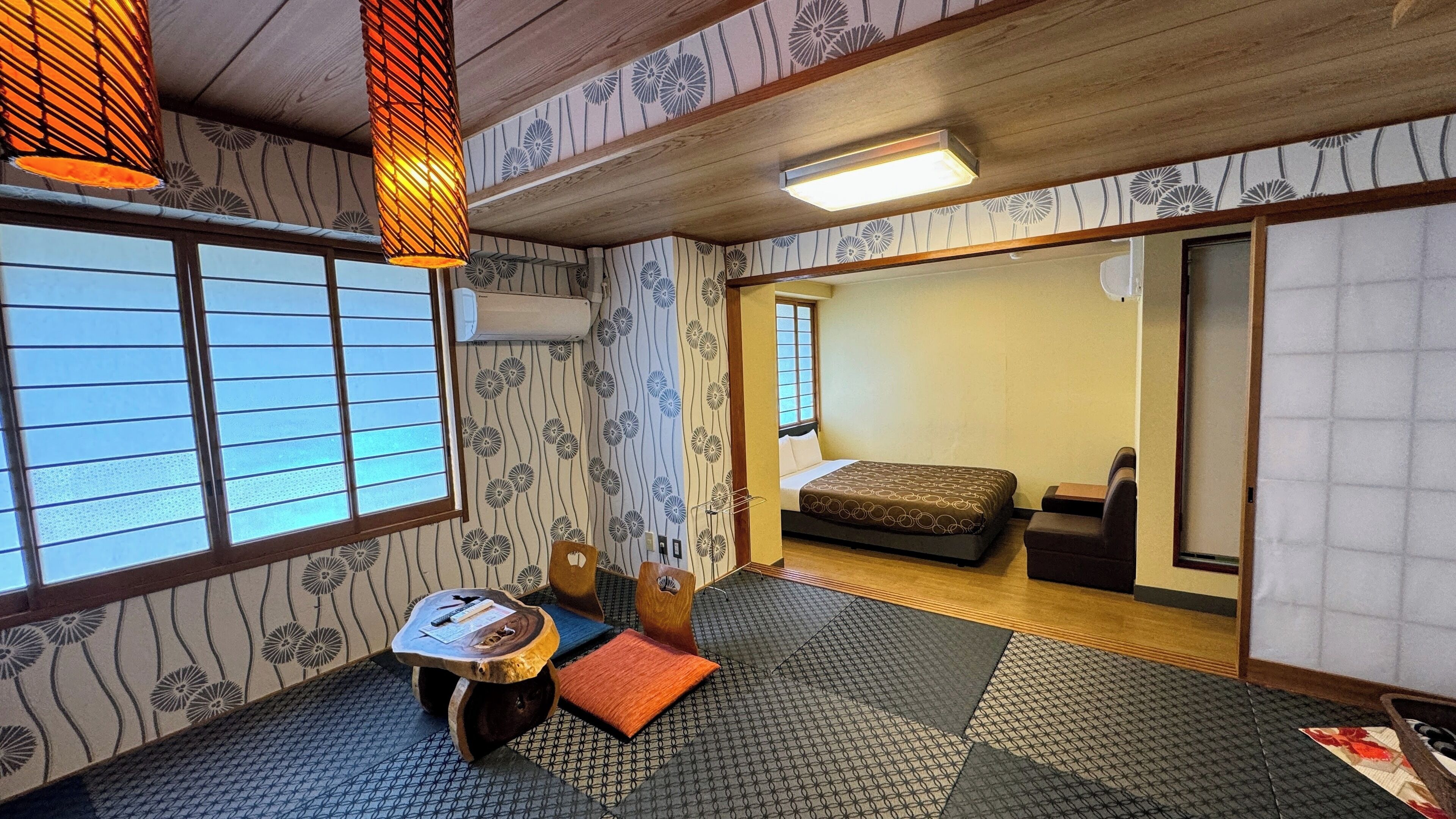 A traditional Japanese-style room with tatami flooring, a futon bed, a low wooden table, and a shoji screen.