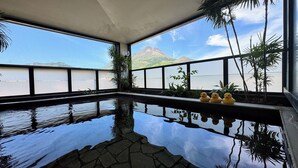 Une piscine intérieure offrant une vue dégagée sur une montagne et un plan d’eau à l’extérieur.