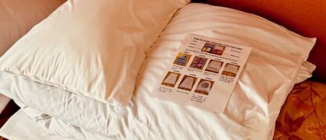Una cama bien tendida con una almohada y una tarjeta con instrucciones paso a paso sobre la almohada.