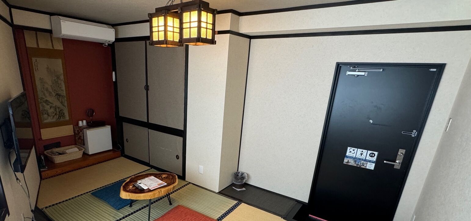 A traditional Japanese room with tatami flooring, a shoji screen door, and a hanging lantern.