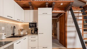 Une cuisine moderne avec des meubles blancs, un four à micro-ondes encastré et un escalier en bois.