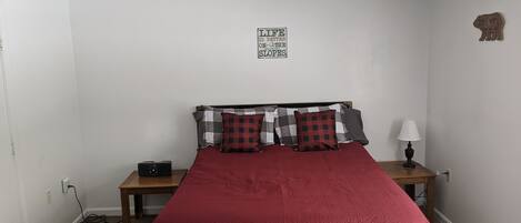 Un dormitorio con una cama, una mesita de noche, una lámpara y un cartel en la pared.