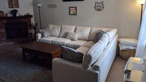 Una sala de estar con un sofá blanco, una chimenea, una lámpara y un letrero que dice "WOODSTOCK, NH".