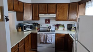 Una cocina con armarios de madera, microondas, estufa y refrigerador.