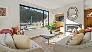 Un salon moderne doté d’une grande fenêtre, d’une cheminée et d’un coin salon confortable.