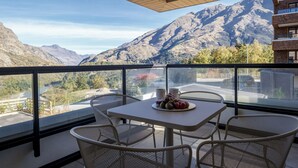 Un balcon avec une table dressée pour deux personnes, offrant une vue sur un paysage montagneux.