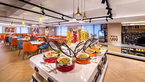 Uma área de buffet com diversas opções de comida, um espaço para café e arranjos de assentos.