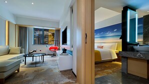 Une chambre d’hôtel moderne équipée d’un canapé, d’une table basse, d’une télévision, d’un lit et d’une salle de bain avec un grand miroir.