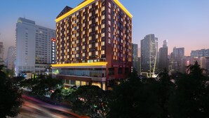 Um hotel de vários andares com design moderno, com várias janelas e uma entrada imponente.