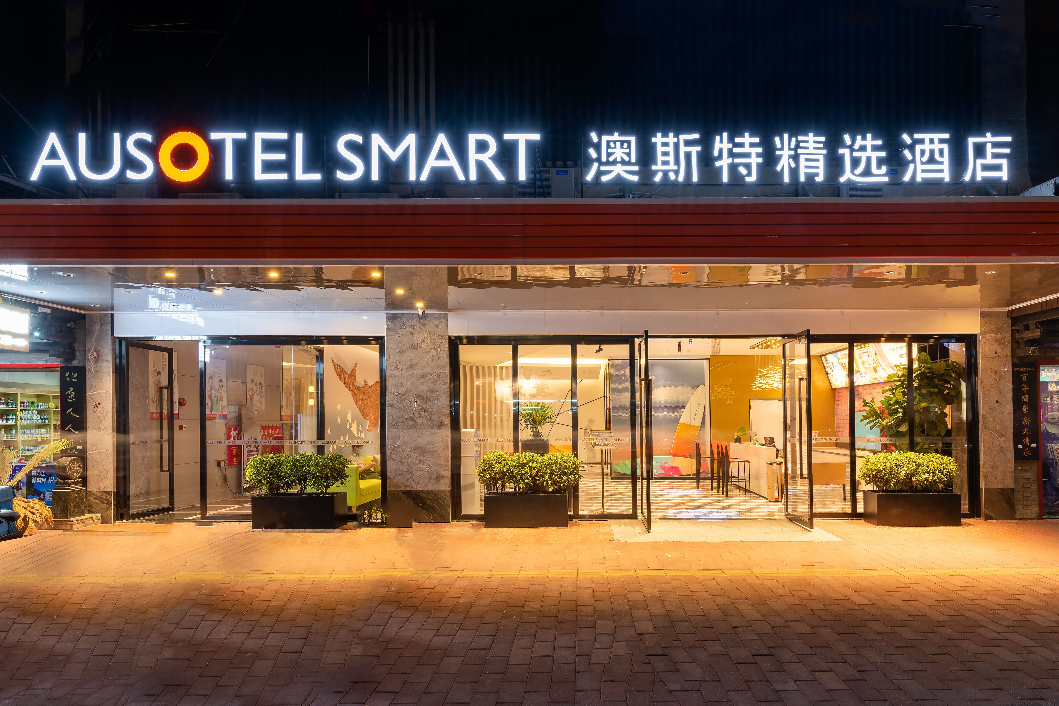 A hotel entrance with a modern design, glass doors, and potted plants.