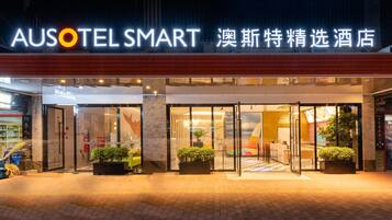 A hotel entrance with a modern design, glass doors, and potted plants.