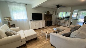 A living room with a sofa, ottoman, and coffee table, a TV, cabinets, and a fireplace. - Relax in the Smokeys, Close to Everything (Whittier)