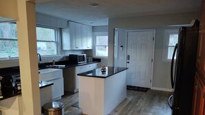 A modern kitchen with white cabinets, a black countertop, and a stainless steel trash can. - Relax in the Smokeys, Close to Everything (Whittier)