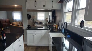 A modern kitchen with white cabinets, a black countertop, and a window providing natural light. - Relax in the Smokeys, Close to Everything (Whittier)