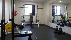 A gym with weightlifting equipment, a bench, and mirrors on the walls. - Motelli Online Oy (Porvoo)