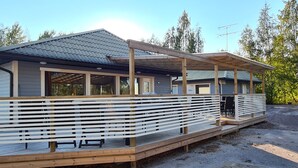 A modern building with a covered patio area, large windows, and a wooden deck. - Motelli Online Oy (Porvoo)