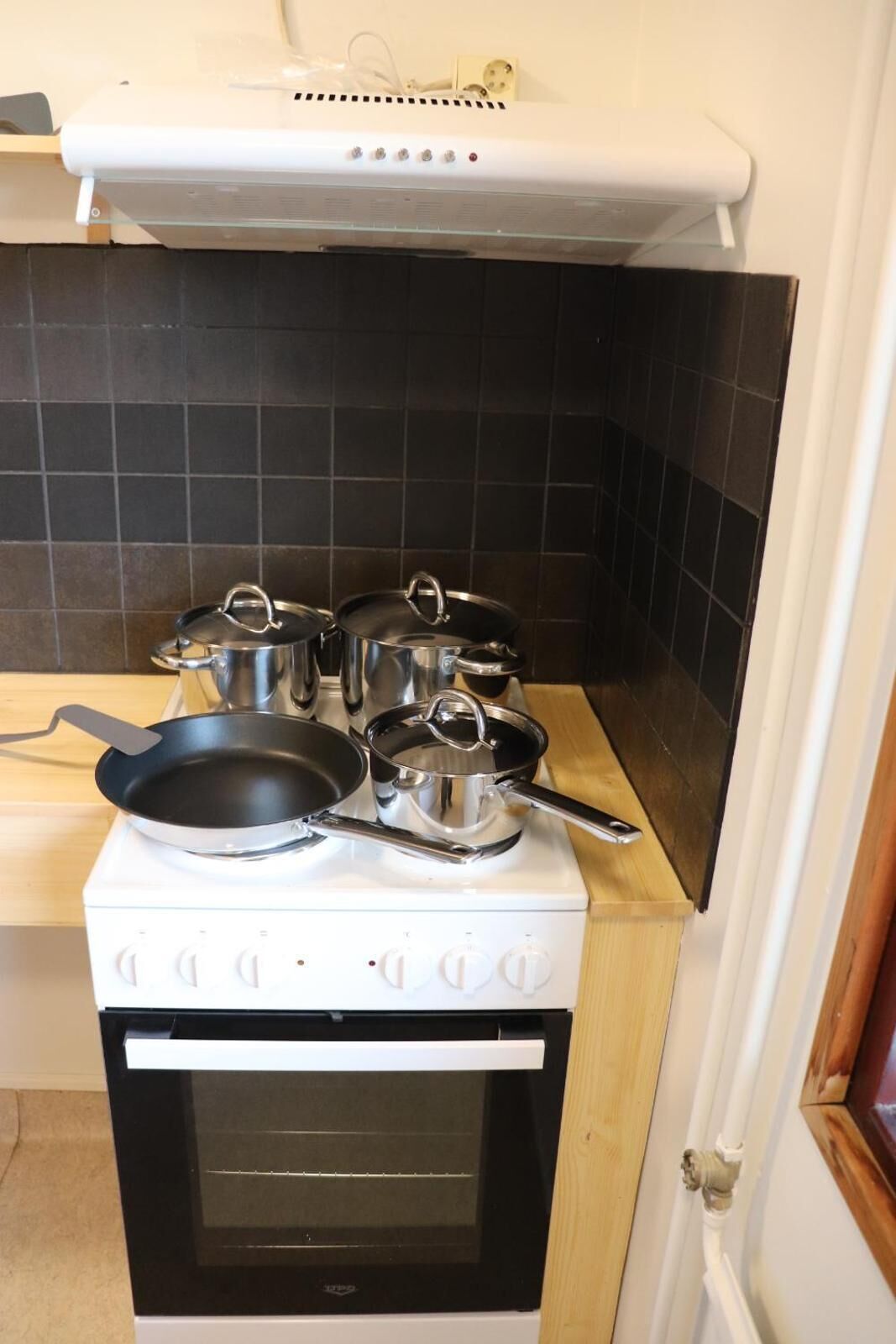 A kitchen with a stove, pots, pans, and a microwave.