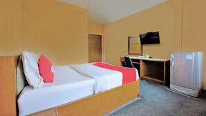 A hotel room with a bed, a desk, a chair, a television, and a refrigerator. - OYO 588 Rose In Mansion (Trang)
