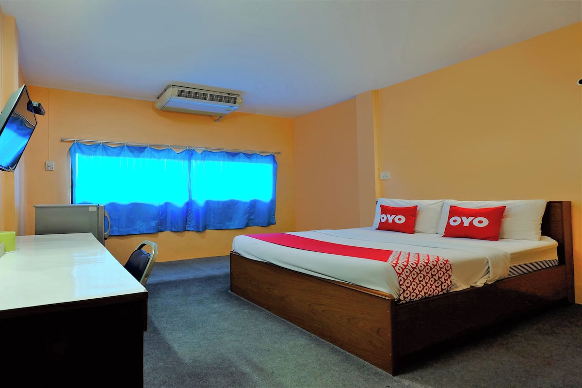 A hotel room with a bed, a desk, a chair, a television, and a window with curtains.