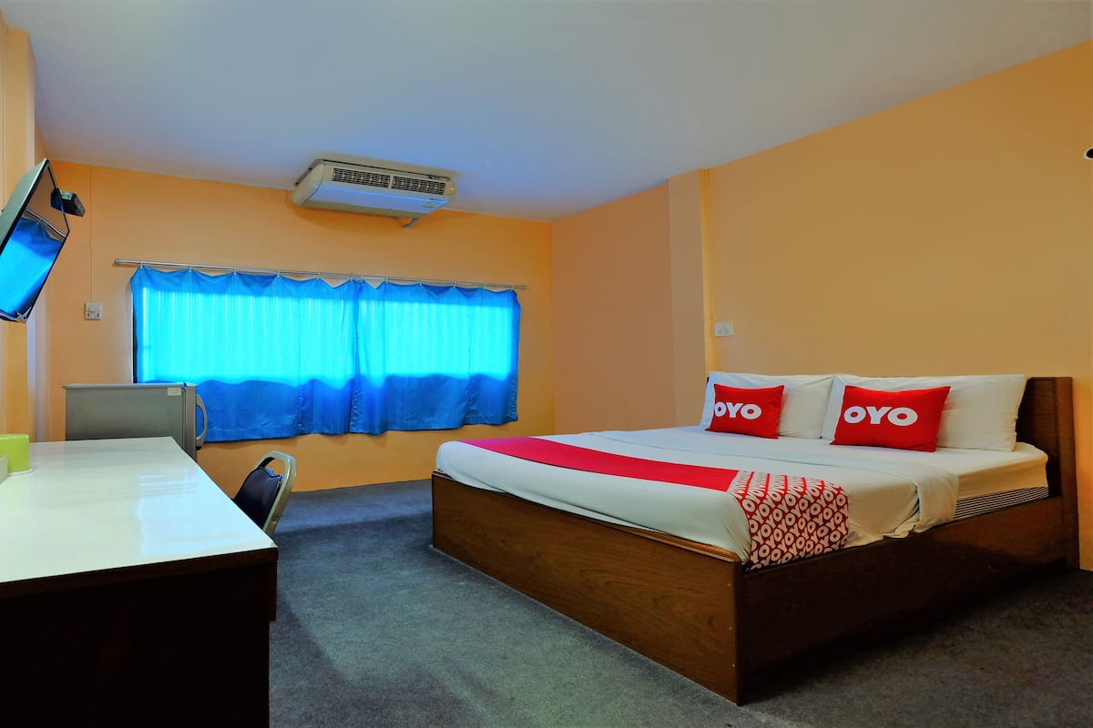 A hotel room with a bed, a desk, a chair, a television, and a window with curtains.