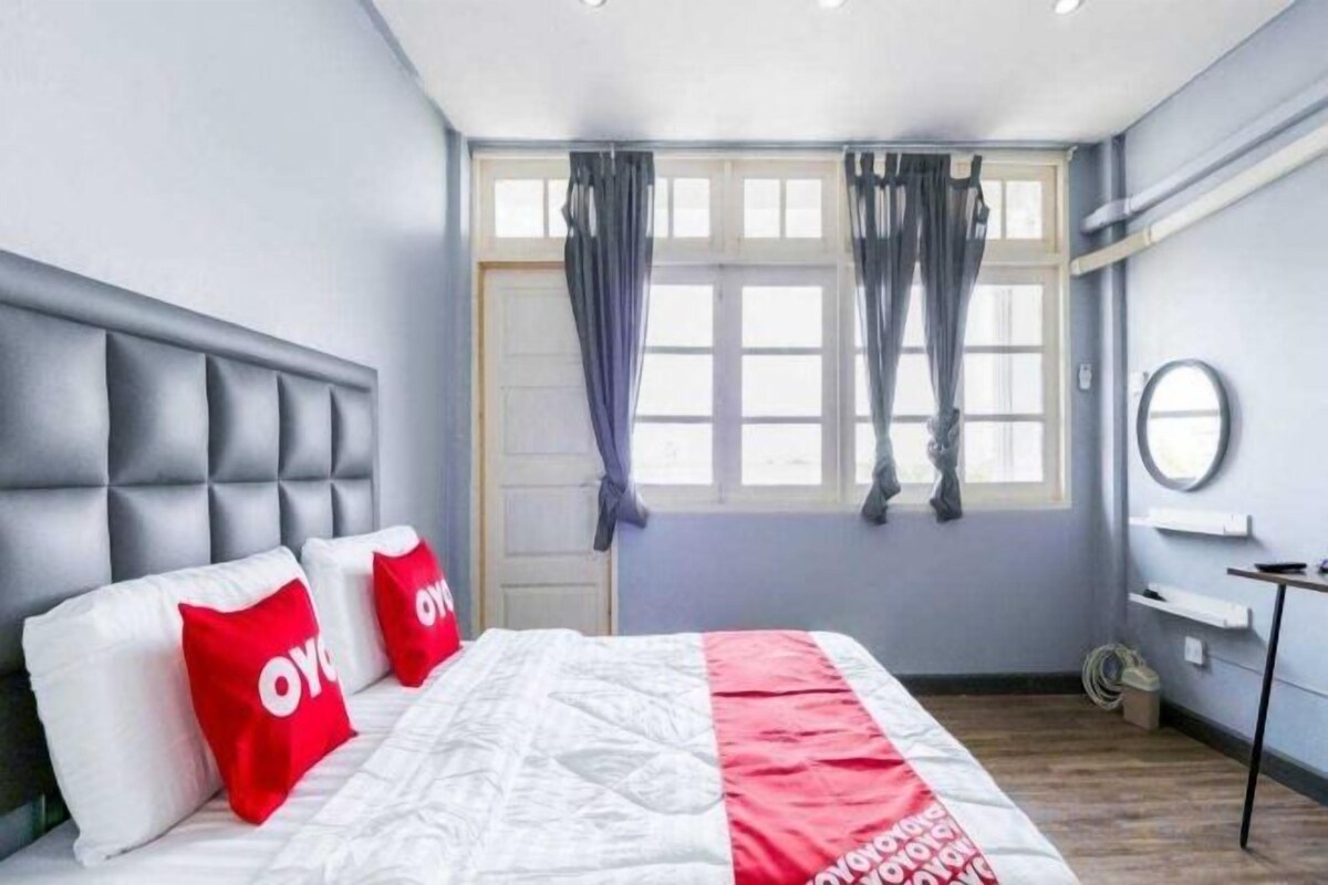 Un dormitorio moderno con una cama, una mesita de noche, una ventana con cortinas y un espejo redondo montado en la pared.