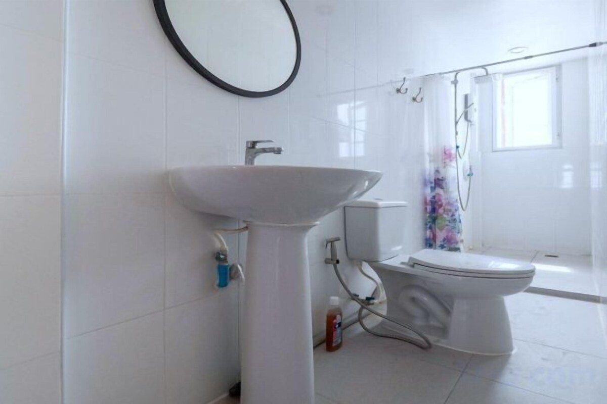 A bathroom with a pedestal sink, toilet, and shower curtain.