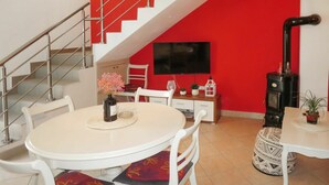 Un espace repas avec une table ronde, des chaises blanches et un mur d’accent rouge.