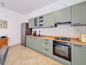 Cozinha com armários verde-claros, bancada de madeira, forno embutido e pia.