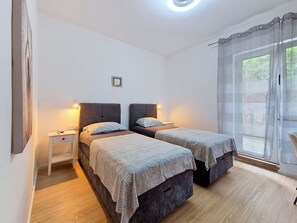 Ein Schlafzimmer mit zwei Betten, einem Nachttisch und einem Fenster mit Vorhängen.