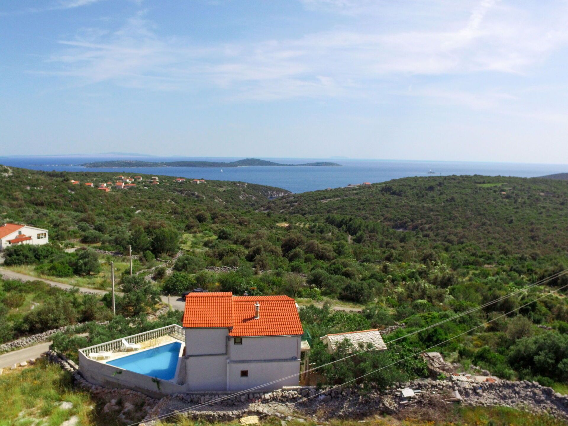 A coastal property with a swimming pool, a red-roofed building, and a view of the sea.
