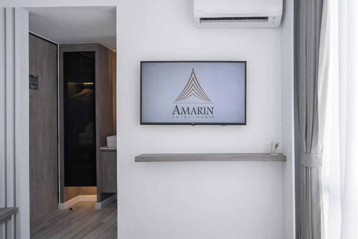A framed logo of 'AMARIN' on a wall, a door leading to a room, and a small shelf below the logo.