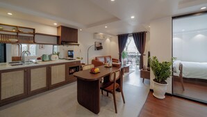 Una cocina moderna con zona de comedor, una planta grande en maceta y un balcón con cama.