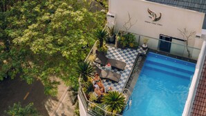 Vista aérea de un hotel con piscina, mobiliario exterior y abundante vegetación.