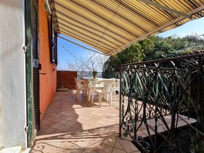A covered patio area with a tiled floor, a table with chairs, and a metal railing. - Beautiful private villa for 5 guests with pool, TV, terrace and pets allowed (Dolcedo)
