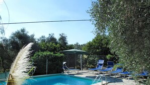A swimming pool with stone tiles, surrounded by lounge chairs and a pergola. - Beautiful private villa for 5 people with pool, TV, terrace and pets allowed (Dolcedo)