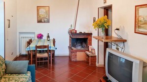 A living room with a fireplace, a dining table with chairs, a sofa, and a television. - Beautiful private villa for 5 people with pool, TV, terrace and pets allowed (Dolcedo)