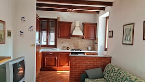 A compact kitchen with wooden cabinets, a tiled backsplash, and a brick wall. - Beautiful private villa for 5 people with pool, TV, terrace and pets allowed (Dolcedo)