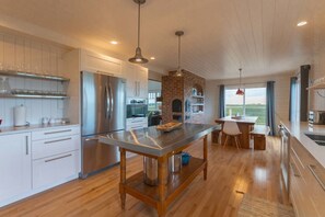 A modern kitchen with stainless steel appliances, a central island, and a brick oven.