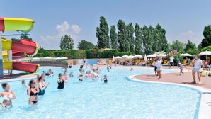 Une piscine dotée de plusieurs toboggans et d’un espace extérieur aménagé avec des chaises longues et des parasols.