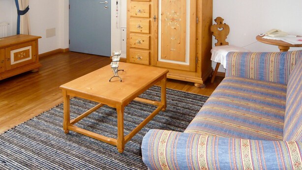 A room with a wooden cabinet, a sofa, a small table, and a blue door.
