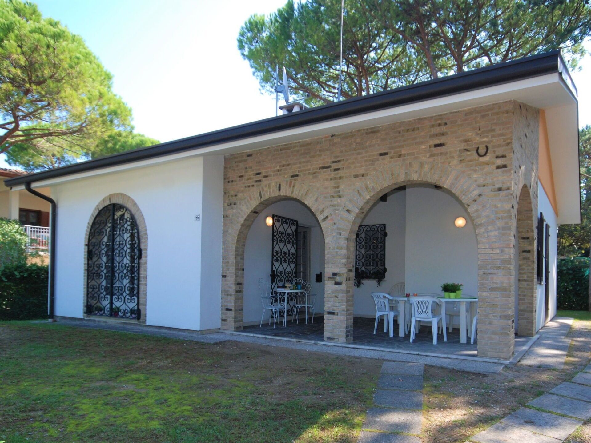 Ein Gebäude mit Ziegelaußenwand, Rundbogenöffnungen und einer Terrasse mit Gartenmöbeln.