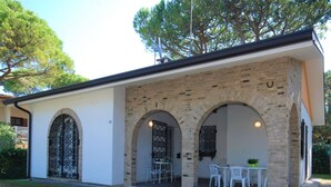Un bâtiment à la façade en briques, doté de portes en arc de cercle et d’un patio aménagé avec du mobilier d’extérieur.