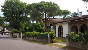 Une rue résidentielle bordée de maisons, dont certaines sont dotées d’un toit en tuiles, de fenêtres en arc de cercle et d’une entrée fermée par un portail.