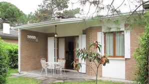 A house with a covered patio, a brick exterior, and a small tree in the front yard. - Beautiful  villa for 6 people with A/C, TV, terrace and pets allowed (Lignano Sabbiadoro)