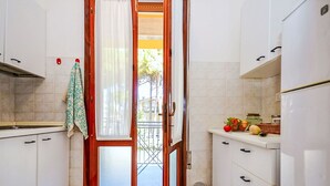 A kitchen with white cabinets, a wooden door, and a view of the street outside. - Lovely apartment for 8 guests with A/C, TV, terrace and pets allowed (San Michele Al Tagliamento)