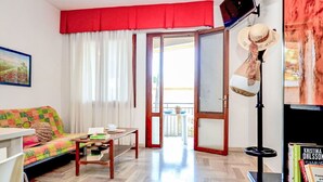 A living room with a sofa, a coffee table, a TV, and a bookshelf. - Lovely apartment for 8 guests with A/C, TV, terrace and pets allowed (San Michele Al Tagliamento)